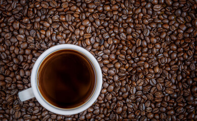 Coffee cup on Coffee beans texture background. Top view
