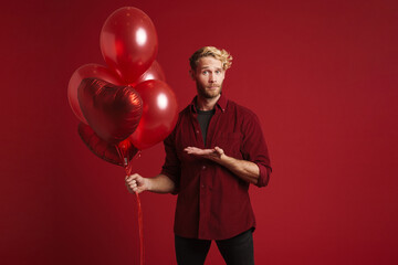 Bearded blonde man holding copyspace while posing with balloons