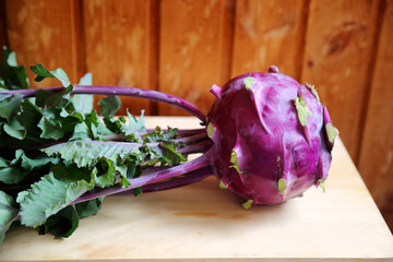 Purple kohlrabi cabbage lays on a wooden board