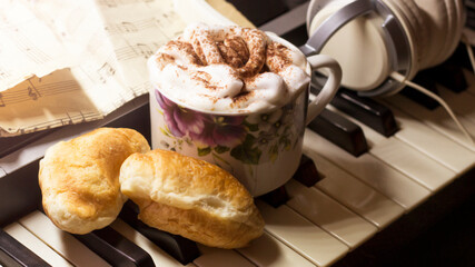 A cup of cappuccino, croissants and headphones, music