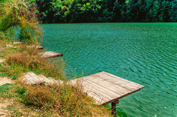 Beautiful summer landscape in the mountains with an azure lake surrounded by forest and a wooden pier