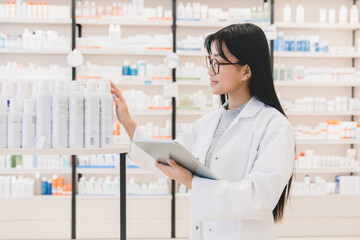 Asian female beautiful young pharmacist druggist checking learning goods, medicines, drugs,...
