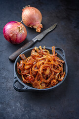 Traditional fried crispy onions rings backed in flour with chili served as close-up in a rustic...