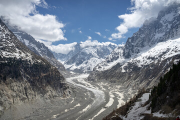 Fototapeta premium A view of the mountain peaks and clouds at the Mer de Glace in Chamonix, France on a sunny summer day in the French Alps