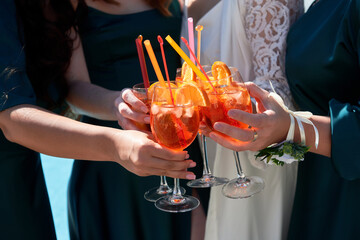 Women hands toasting with aperol spritz cocktails on summer party, copy space. Event celebration concept. Hen party. Traditioanal italian aperitif.
