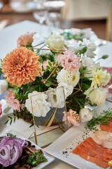 Beautiful floral arrangement of rose flowers and greenery on wedding table in restaurant, copy space. Luxury wedding decorations. Table setting