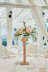 Beautiful floral arrangement of rose flowers and greenery on wedding table in restaurant, copy space. Luxury wedding decorations. Table setting