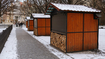 Closed Christmas market stalls in Prague, Czechia. Event is canceled due to coronavirus pandemic. Classic wooden stalls for sale of mulled wine, chestnuts, handicrafts and souvenirs.