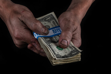 A bundle of old 1 American dollar bills in the dirty hands of a working man