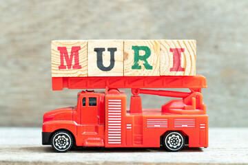 Fire ladder truck hold letter block in word muri on wood background