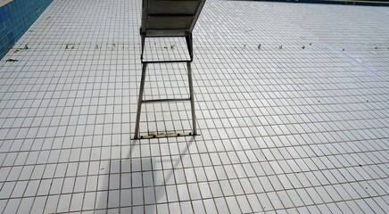 Wasserrutsche von hinten im Schwimmbecken ohne Wasser mit weißen Kacheln im Schwimmbad im Sommer