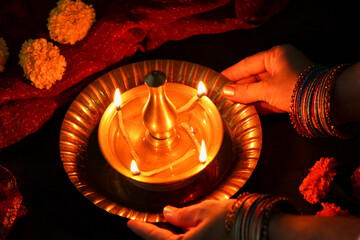 Indian woman holding lighting oil lamp Pongal Onam Diwali vishu celebration Indian festival decorating marigold flowers Nilavilakku Rangoli Dipavali Kerala Tamil nadu North India Mumbai Delhi India