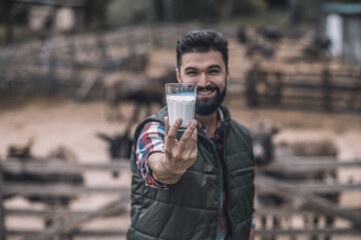A bearded farmer holding a glass of milk