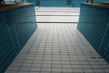 Schwimmbecken ohne Wasser mit weißen und blauen Kacheln im Schwimmbad im Sommer