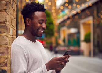 Male Vlogger Or Social Influencer In City Using Mobile Phone On Street To Post To Social Media