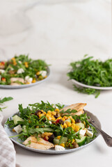 Plate of salad arugula leaves, canned corn, chicken, cucumber and feta cheese. Salad bowl, healthy food. Fresh salad