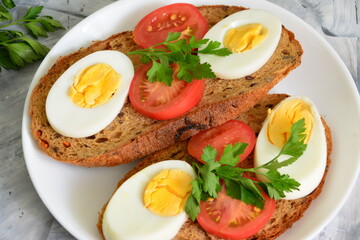Fototapeta na wymiar healthy sandwiches with boiled eggs, tomatoes and parsley, close-up