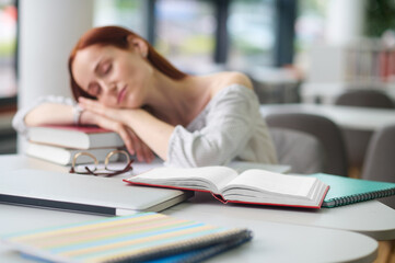 Woman at table laid head on books asleep