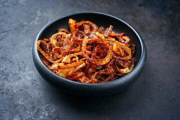 Traditional fried crispy onions rings backed in flour with chili served as close-up in a rustic...