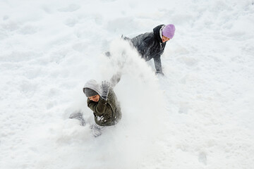 Boy and girl, teenagers, brother, Sister indulge, roll around in snow on snowy day In winter,...
