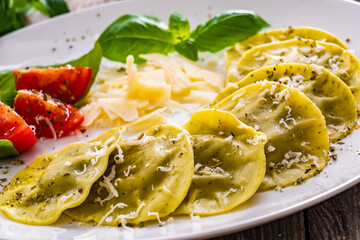Medaglioni with cheese, basil and pine nuts on wooden table

