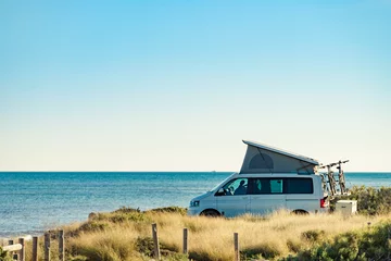 Poster Im Rahmen Camper van with roof top tent camp on beach © Voyagerix