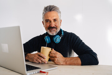 Aged blogger resting with cup of tea in studio
