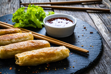 Spring rolls on stone plate on wooden table