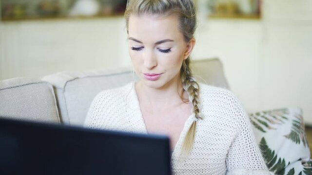 Young blonde woman working with computer at home.