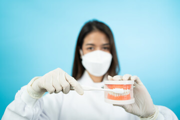 Front view selective focus of hands wearing white medical gloves of Asian female dentist in face...
