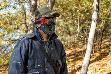 A man wearing respirator mask and protective glasses walking in the forest at COVID-19 period.