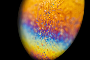 Extreme closeup soap bubble, like multicolor abstract round alien planet in universe on dark...