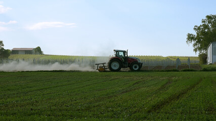 Fototapeta premium Tractor driving on track with a trail of dust