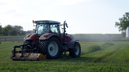 Tractor cultivating a field with a trail of dust