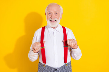 Photo of cute old man wear white shirt red suspenders isolated on yellow color background