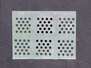 Metal ventilation grill on a gray wall close up
