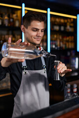 Bartender in apron adds ingredient to glass