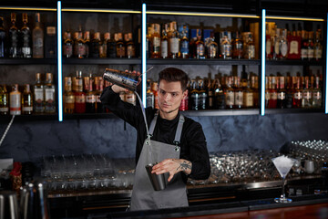 barman is making cocktail with steel shaker