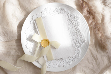 White card mockup on plate with beige ribbon 