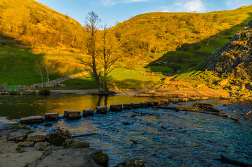 The view at sunset of stepping stone across the River Dove at Dovedale, UK on a sunny Autumn evening