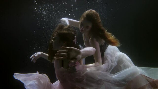 mysterious lesbians under the water in dresses swim like fabulous mermaids