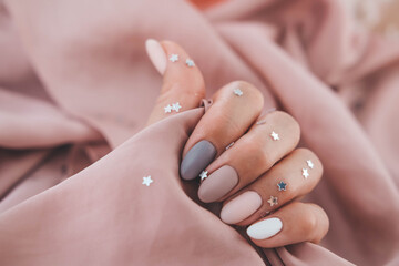 Women - hand with beautiful manicure hold a silk fabric. Autumn trend, polish the beige and quail...