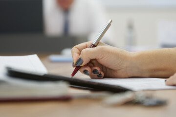 Woman with a black manicure writes a document, contract or resume, fills out the form with a fountain pen. Without a face. Selective focusing