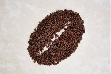 Roasted coffee beans laid out in the form of a large coffee grain on a beige background.