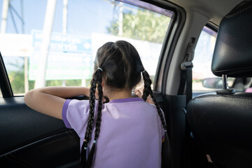 Backside of Little Asian 5 years old girl, is looking to the outside through car window mirror in the afternoon time.