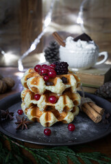 
Waffles with blackberries and currants. Christmas sweets. Table with desserts and Christmas decorations. Still life with sweets