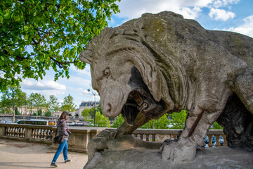 Fototapeta na wymiar Giant lion sculpture roaring at a Person walking by, Park of Louvre Palace in Paris