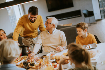 Young man poring red wine to his father for testing during at home