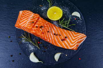 Raw salmon fillet with spices on black slate. Top view