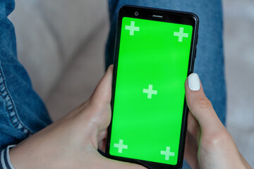 Hands of a girl using a mobile phone with a green chroma screen . Remote access concept.